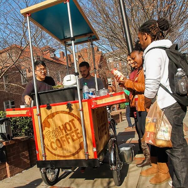 People in line at outdoor coffee cart.
