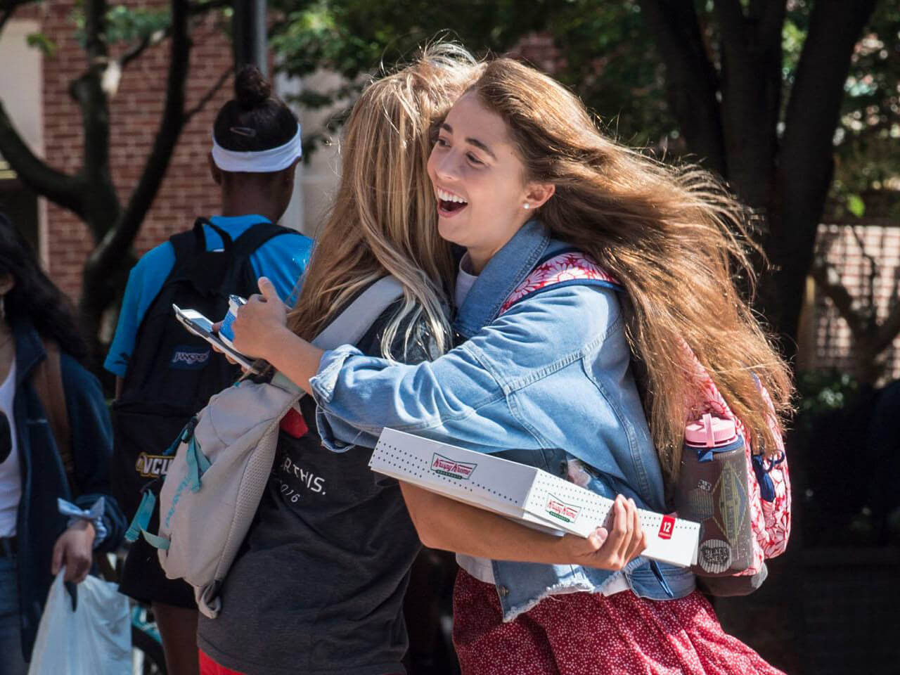Two students hug and smile