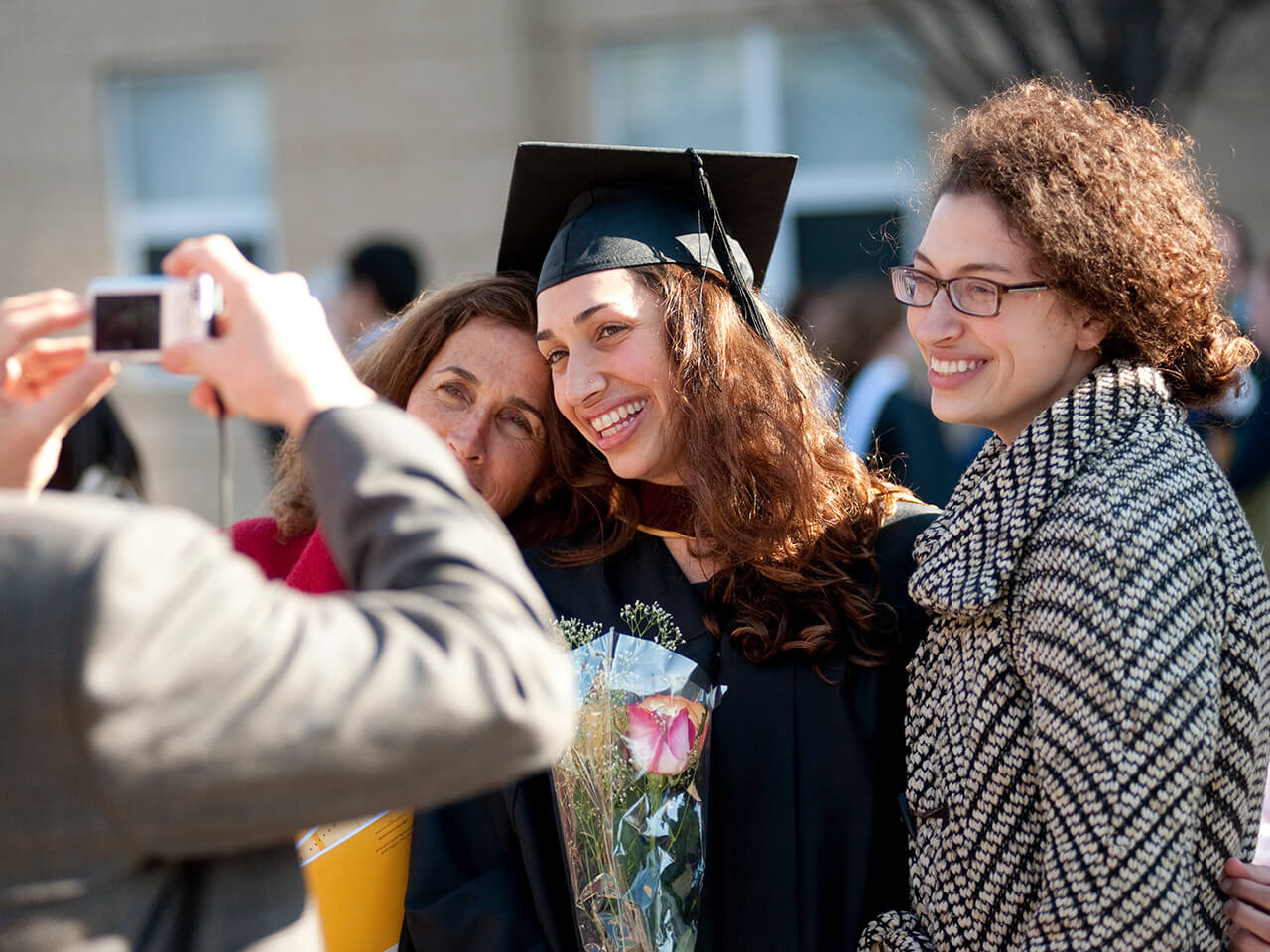 Student graduating wearing cap and gown with family