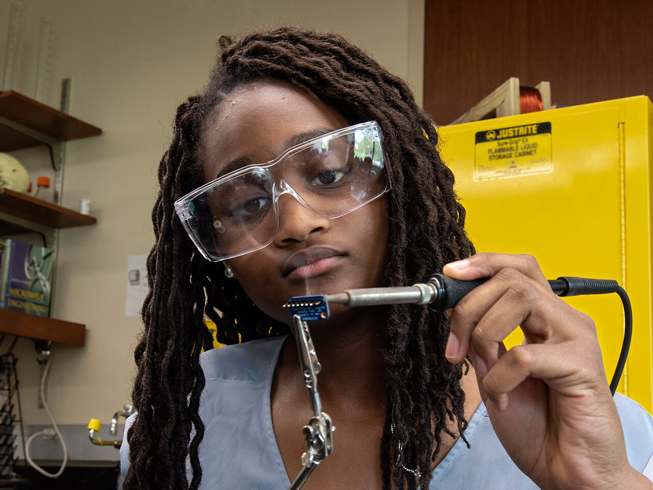 Student working with a tool with protective goggles on