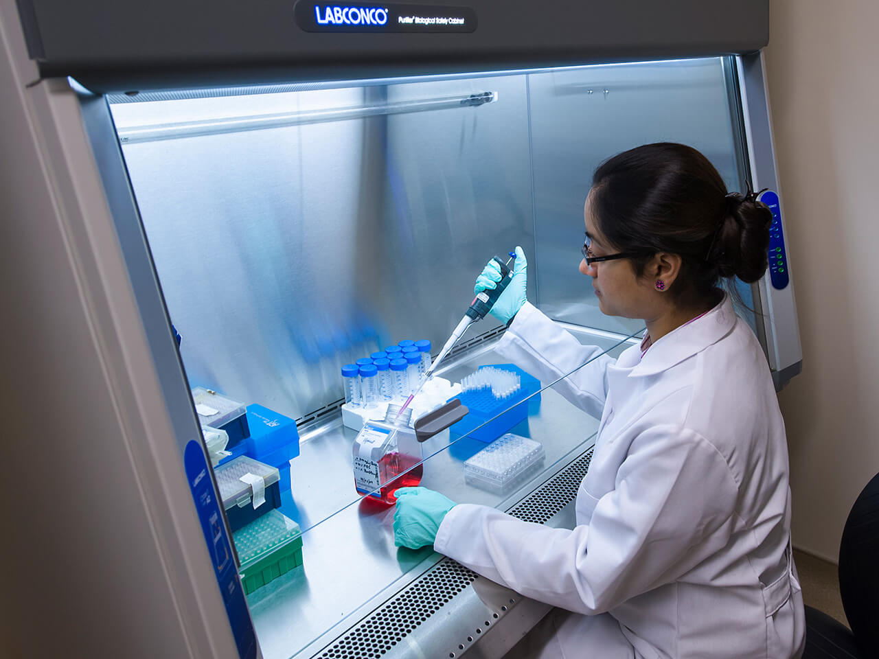 Student works in a lab setting taking samples of a liquid