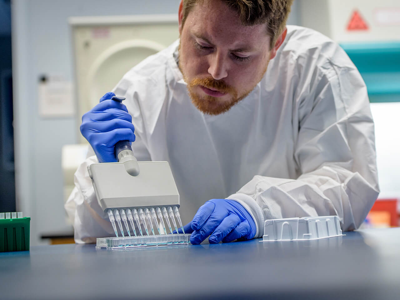 Student wearing gloves while using a lab tool
