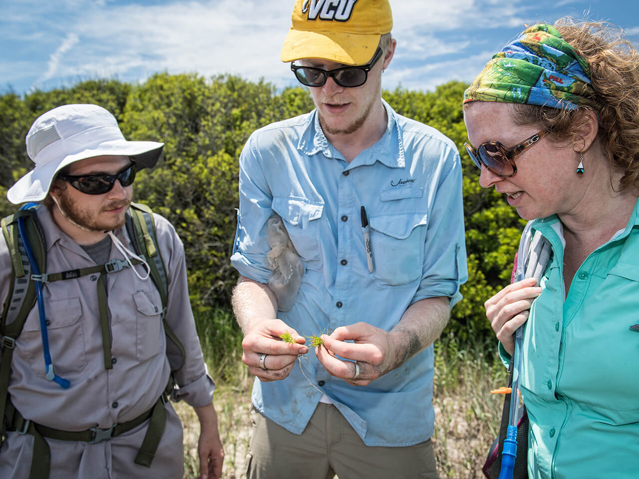 Three people reviewing findings during research at the river