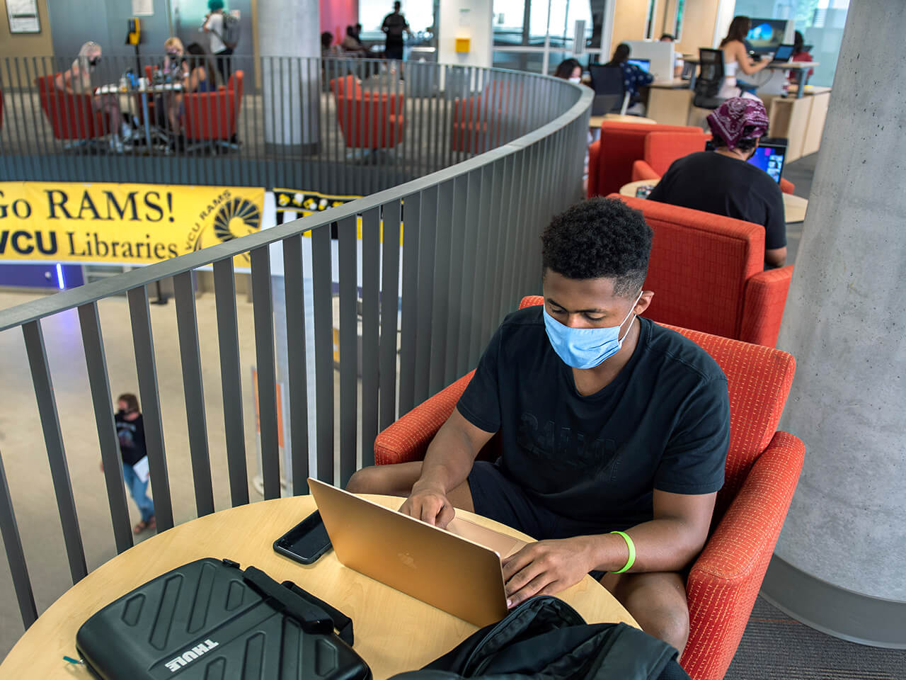 Student working on a laptop sitting on a red chair